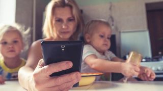 moeder op telefoon met twee jonge kinderen op schoot