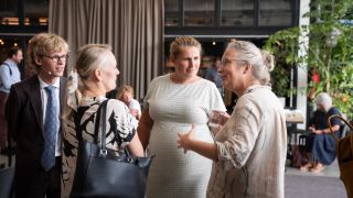 vier personen in gesprrek luisterend naar vrouw die uitlegt