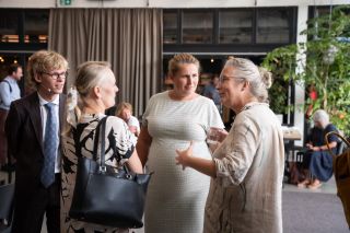 vier personen in gesprrek luisterend naar vrouw die uitlegt