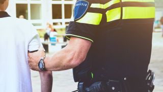 politie houdt een jongen zijn arm vast