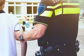 politie houdt een jongen zijn arm vast