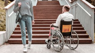 man in een rolstoel voor een trap