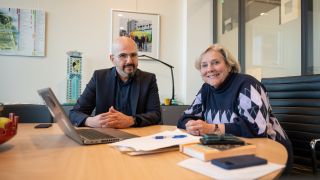 twee mensen aan tafel met een laptop