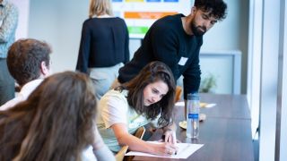 groep in overleg schrijvend aan tafel